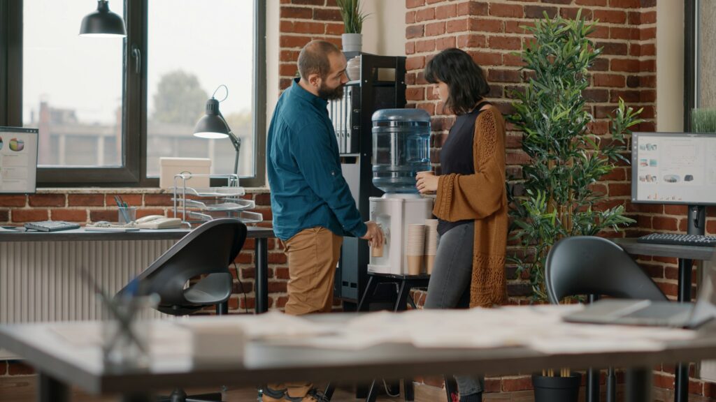 Colleagues meeting on break while having refreshment from water cooler